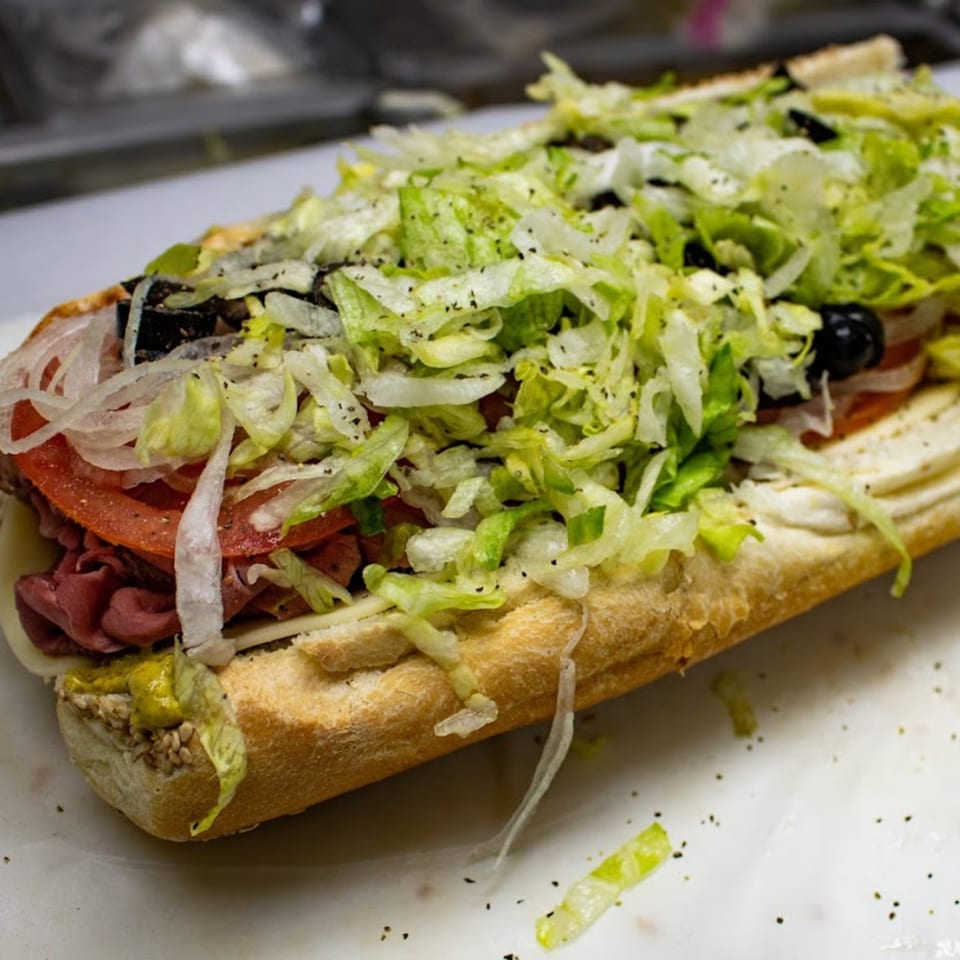 A large Italian deli sub with roast beef, cheese, tomatoes, onions, olives, and shredded lettuce.